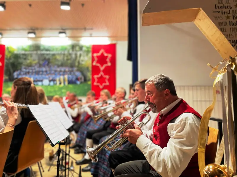 Musikerinnen und Musiker in Tracht spielen Trompete und Querflöte in der weihnachtlich geschmückten Halle