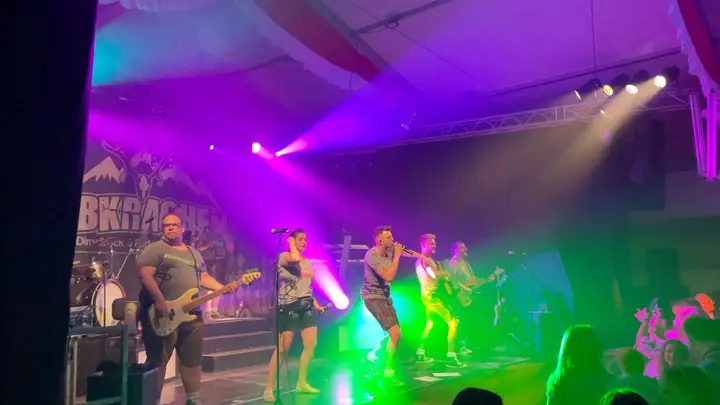 Die Band Albkracher spielt bei bunter Lichtshow auf der Bühne im Festzelt, im Vordergrund feiert das Publikum