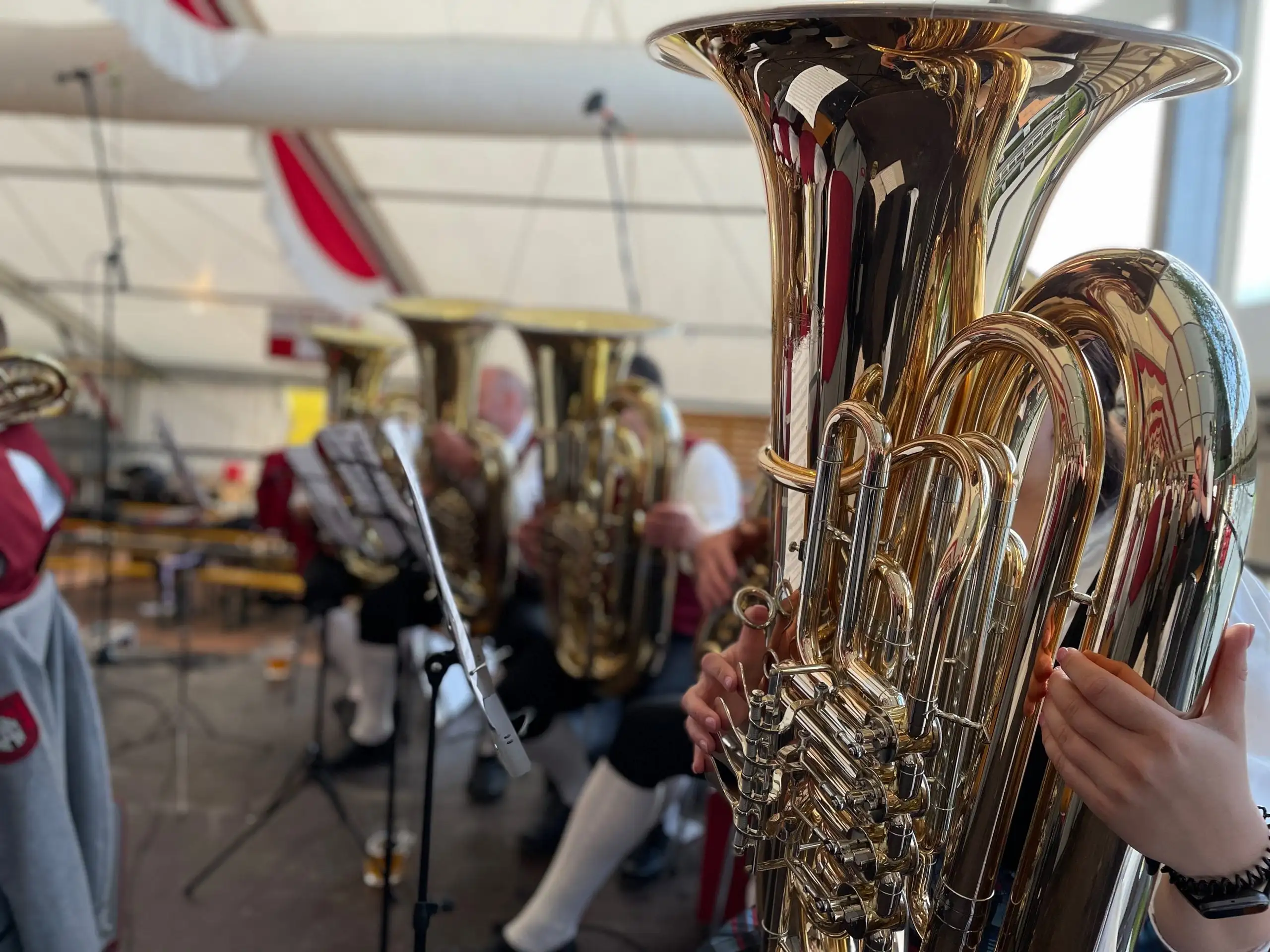 Nahaufnahme einer glänzenden Tuba im Festzelt, dahinter die Kapelle in Tracht